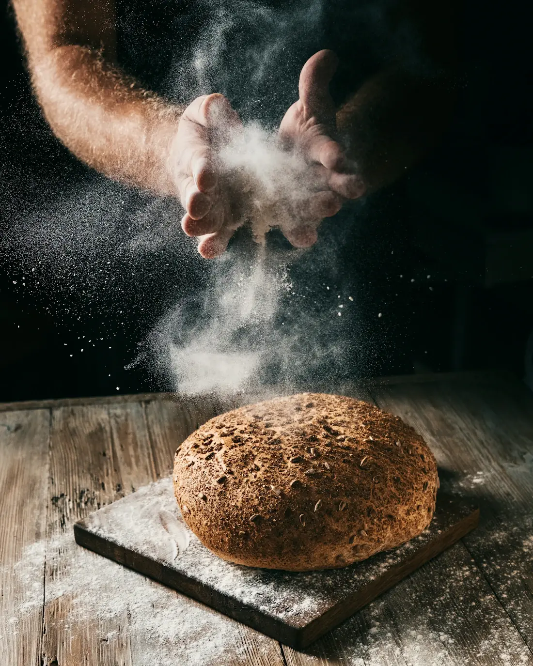 Bakker strooit bloem over een vers brood